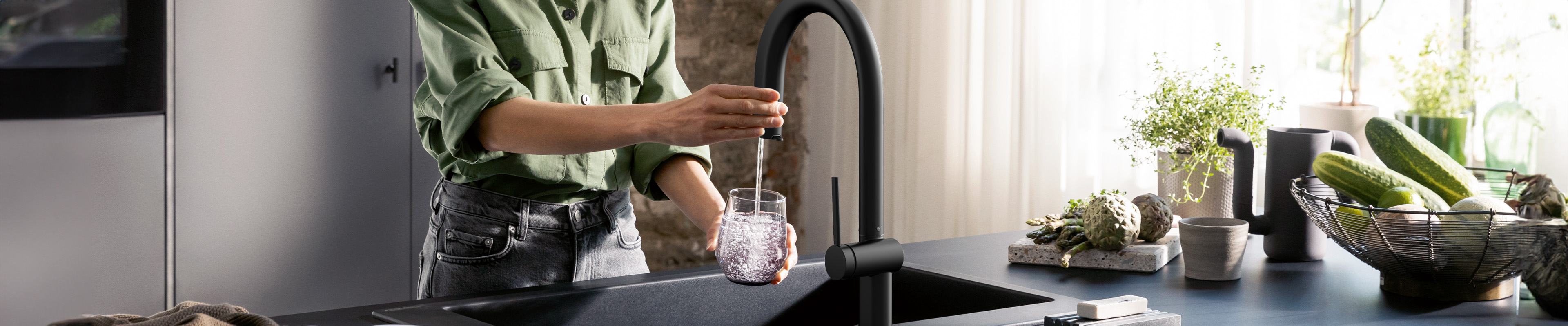 Woman fills a glass of water with Aqittura M91