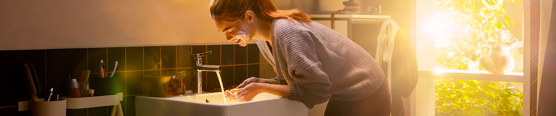 Woman washing her face with hansgrohe Zesis S faucet.